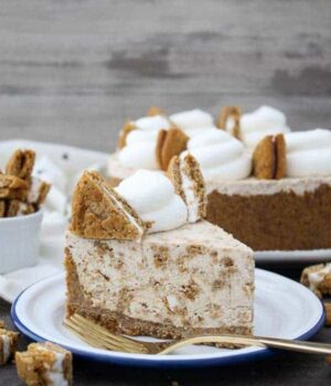 A slice of Oatmeal Cream Pie Ice Cream Pie on a white plate with a blue rim and a gold fork.