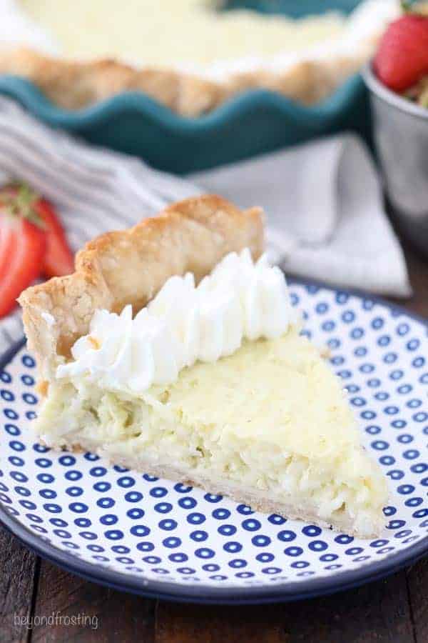 A slice of coconut pie on a blue polka dot plate