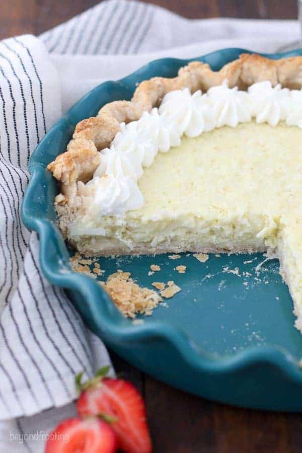 A quarter slice of pie in a teal pie plate decorated with whipped cream