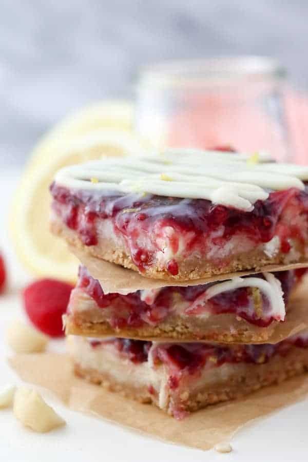 A stack of seven layer bars topped with raspberry jam, lemon zest and white chocolate