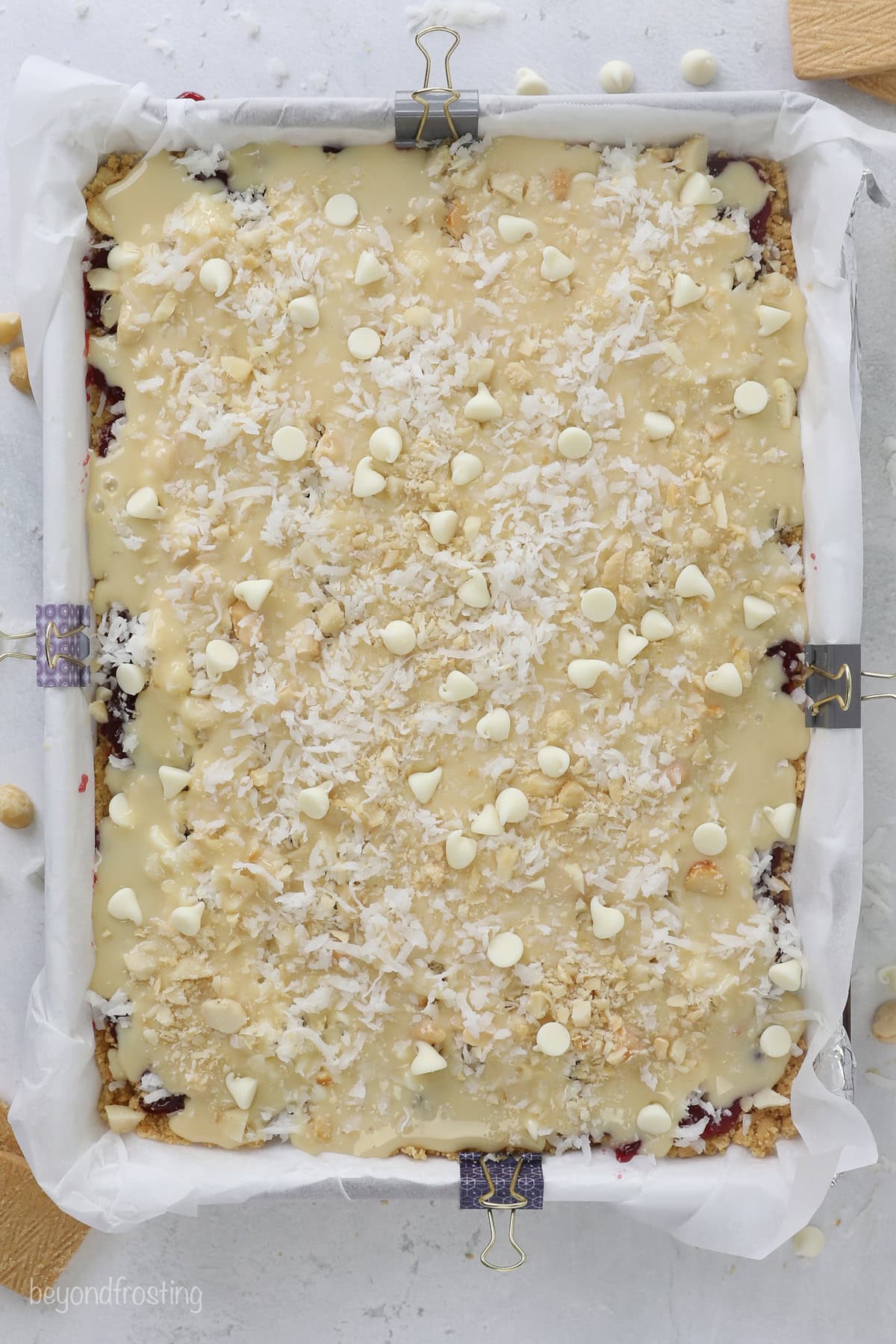 Overhead view of raspberry magic cookie bars assembled in a lined baking pan.