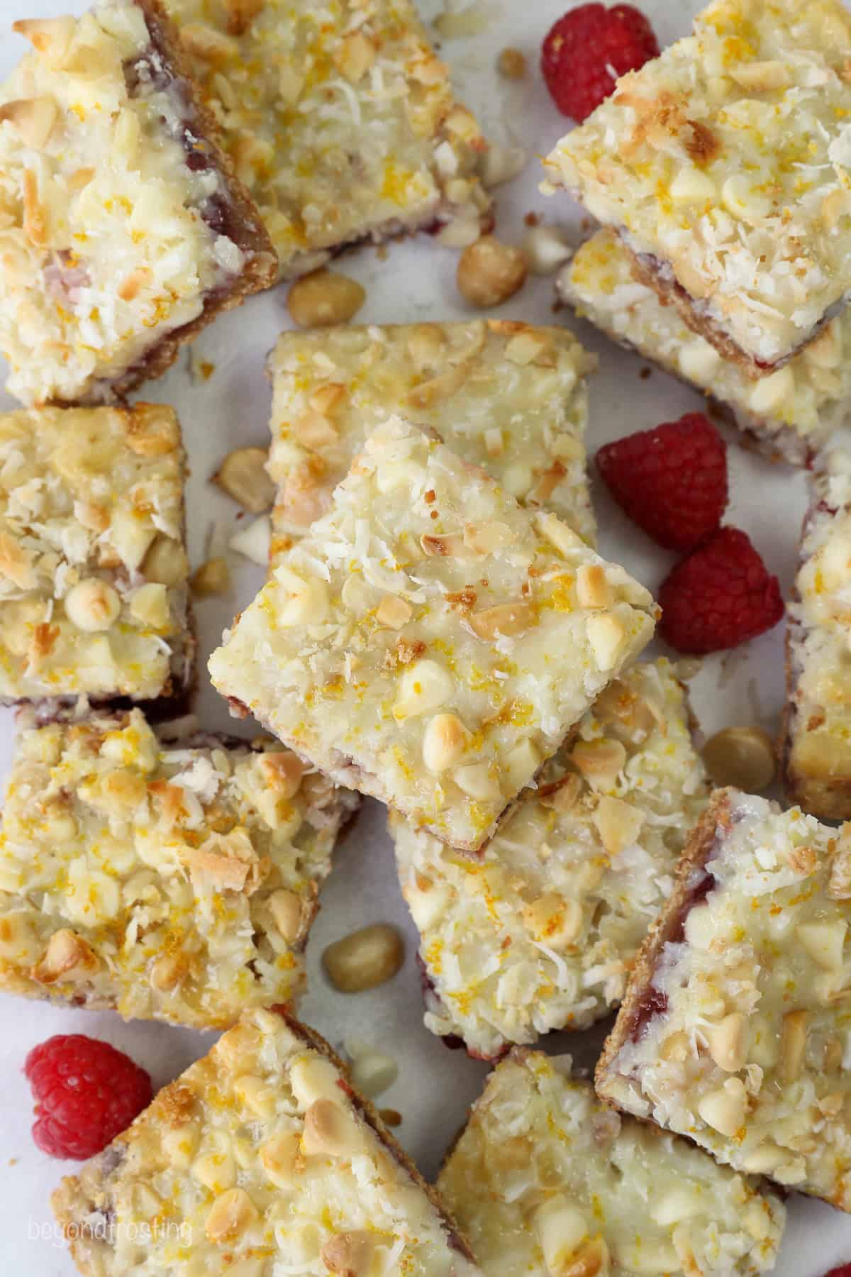 Overhead view of assorted raspberry magic cookie bars next to scattered raspberries.