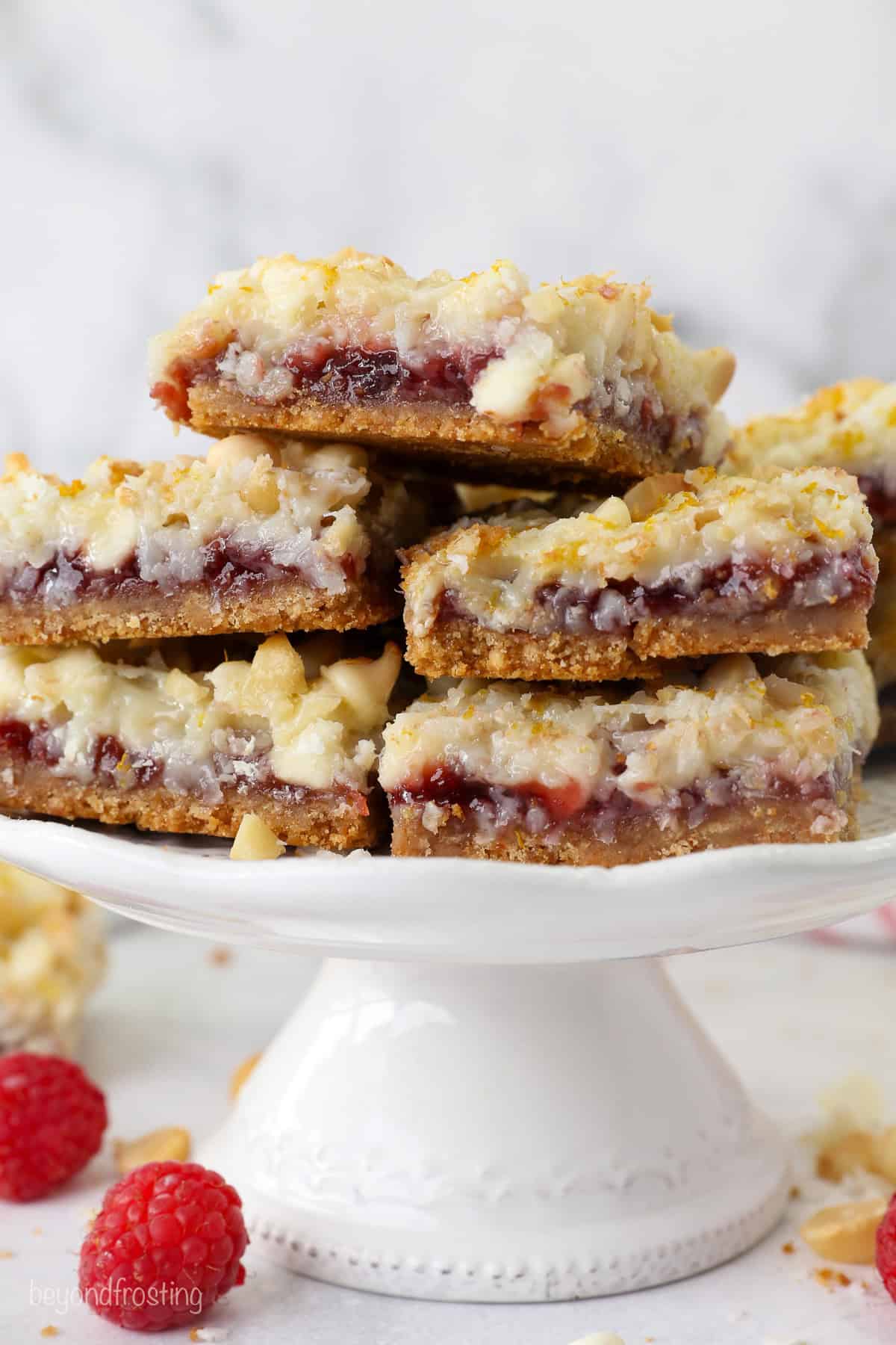 Raspberry magic cookie bars stacked on a white cake stand.