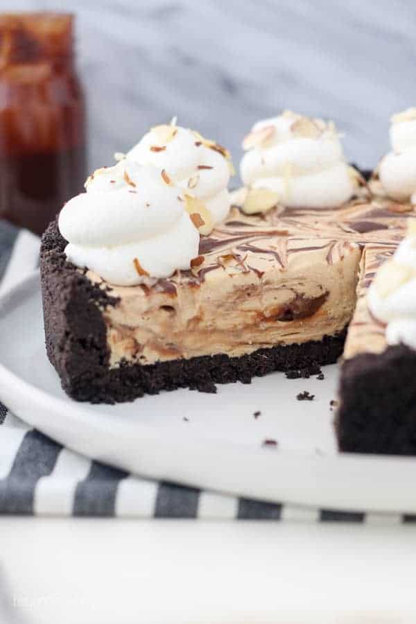 A mocha fudge pie on a large white plate with a slice taken out of it showing the ribbons of fudge in the middle