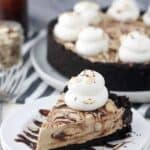 An overhead shot of a slice of mocha fudge pie on a white cake plate drizzled with hot fudge sauce
