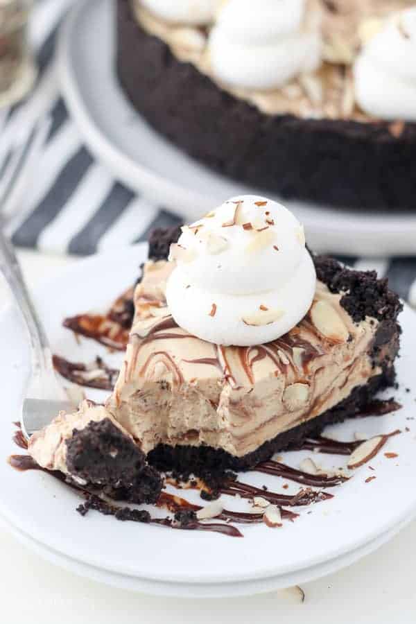 A slice of mocha pie on a plate with a few bites taken out of it showing the swirls of chocolate in each layer.