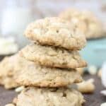 A stack of four large cookies stuffed with white chocolate and nuts