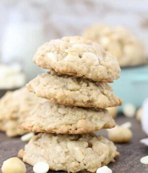 A stack of four large cookies stuffed with white chocolate and nuts