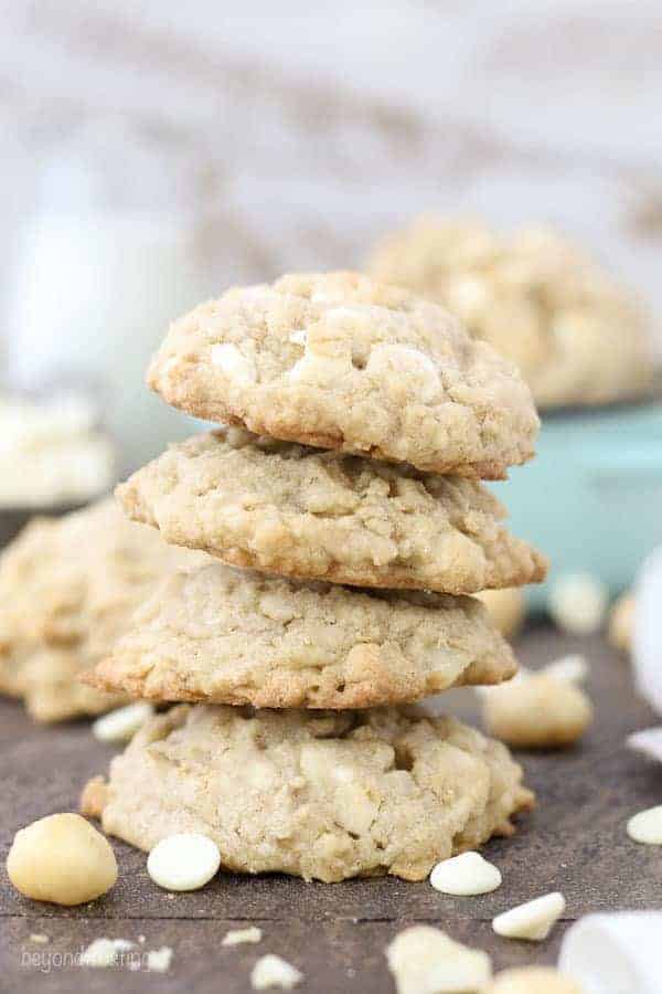 A stack of four large White Chocolate Macadamia Nut Cookies stuffed with white chocolate and nuts