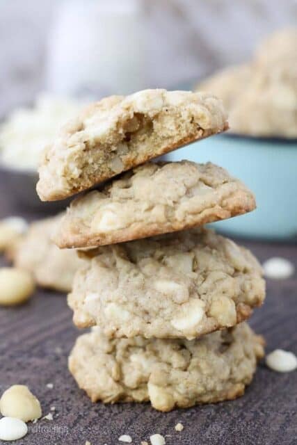 A stack of 4 chunky cookies, the top cookie has a big bite taken out of it