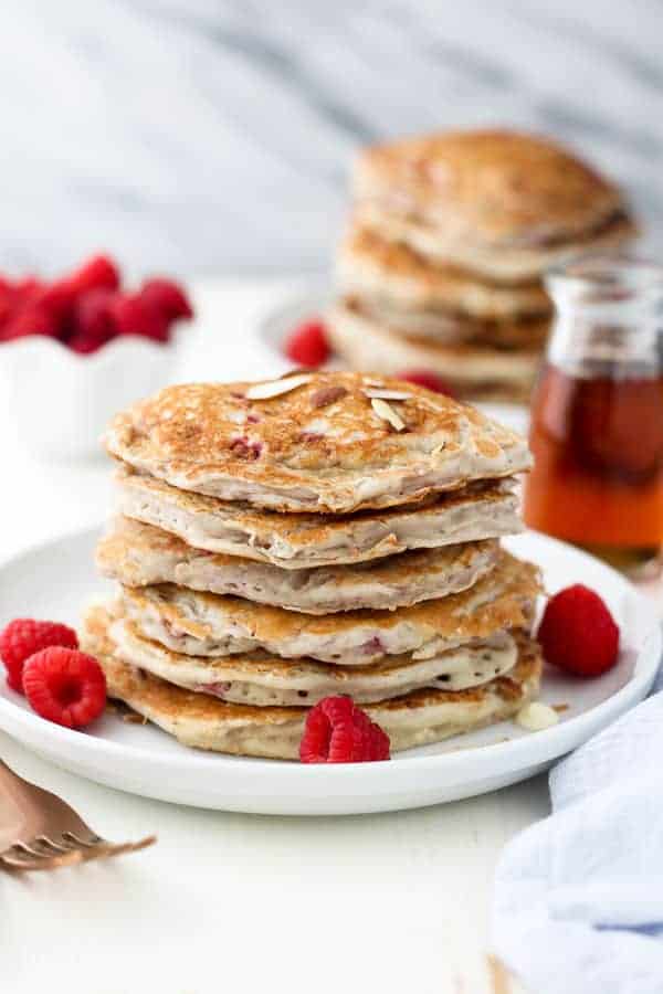 Raspberry Almond Pancakes on a white rimmed plate with fresh berries