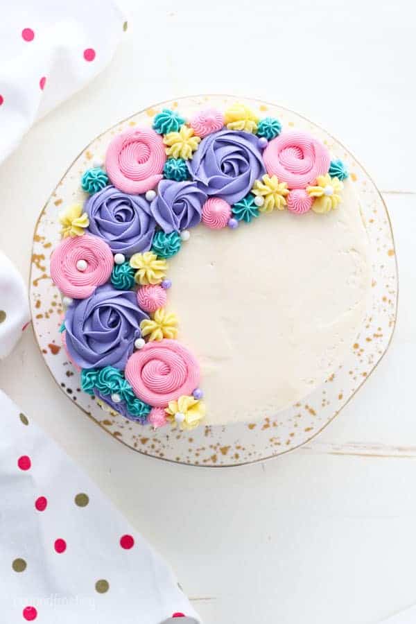 An overhead view of a beautiful cake decorated with pastel color buttercream flowers