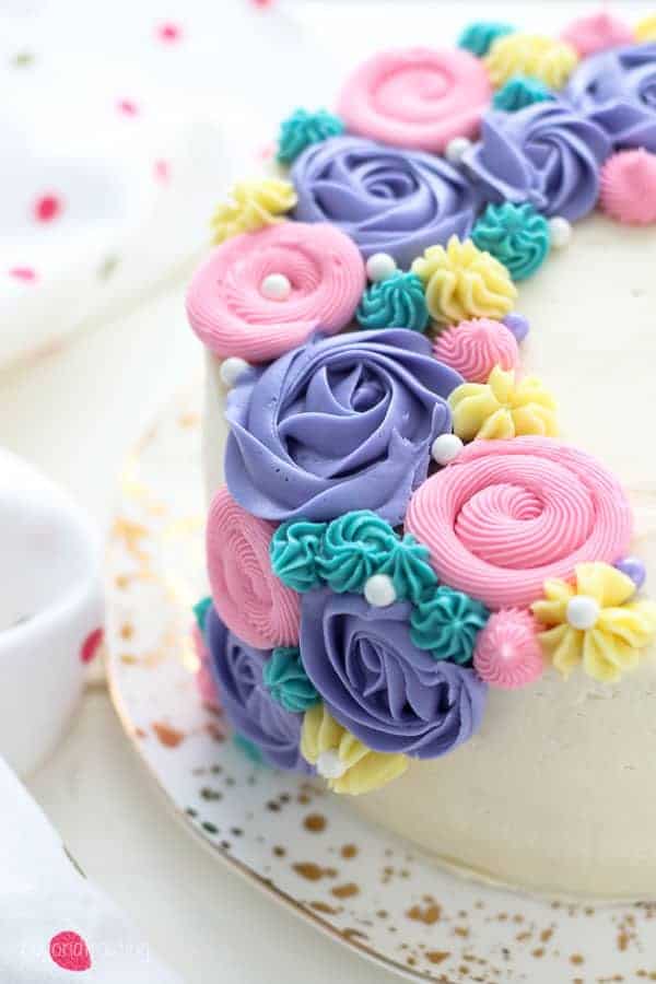 A close up view of a cake decorate with buttercream flowers and buttercream roses