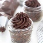 A mini glass jar filled with a chocolate frosting
