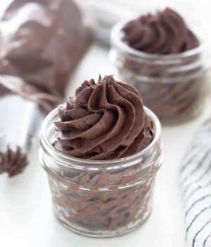 A mini glass jar filled with a chocolate frosting