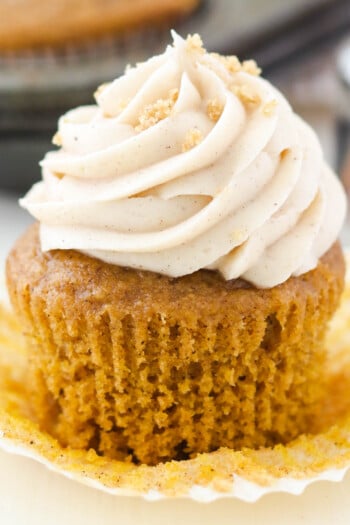 A pumpkin cupcake with cream cheese frosting with the wrapper pulled off