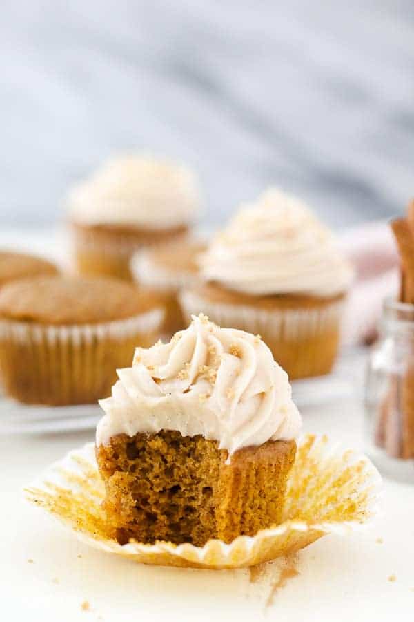 A close up show of a pumpkin cupcake with a giant bite taken out of it.