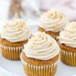 A top down view of cupcakes on a white rimmed plate with a cream cheese swirled frosting