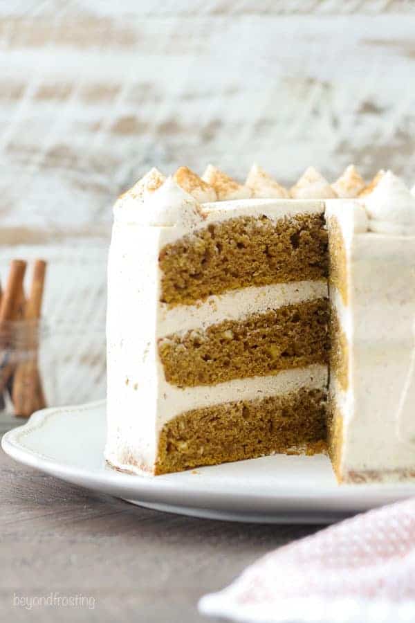 A side view of an 8-inch 3 layer pumpkin cake frosting with mascarpone whipped cream.