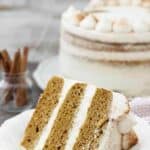 A gorgeous 3 layer pumpkin cake with a whipped mascarpone frosting laying on an off white plate.