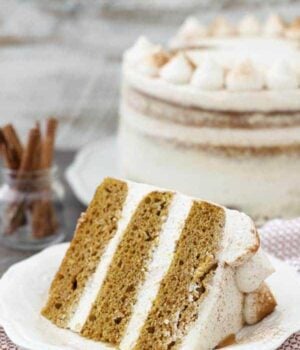 A gorgeous 3 layer pumpkin cake with a whipped mascarpone frosting laying on an off white plate.