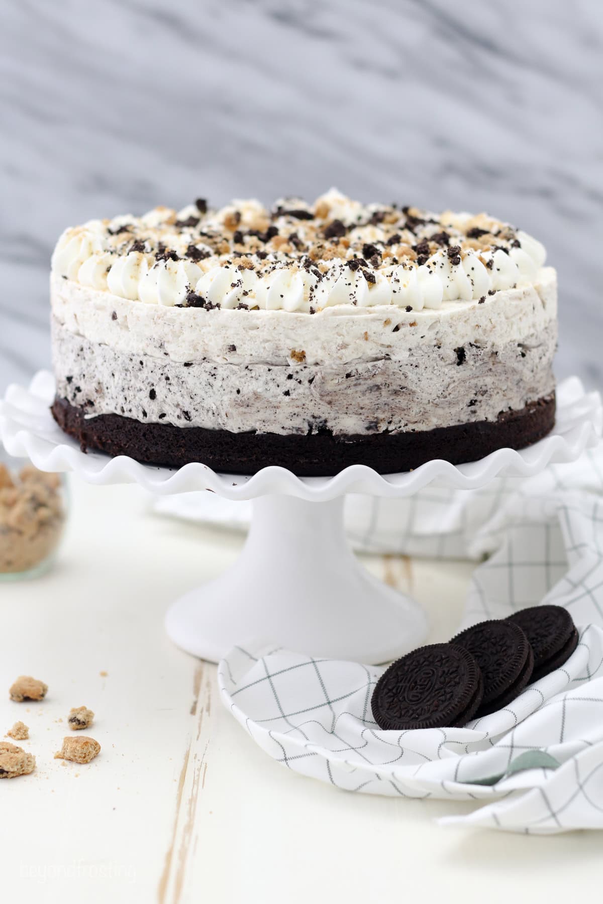 An Oreo brookie mousse cake on a white cake stand.