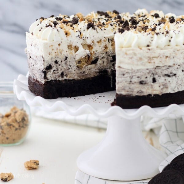 An Oreo brookie mousse cake with a large slice missing on a white cake stand.