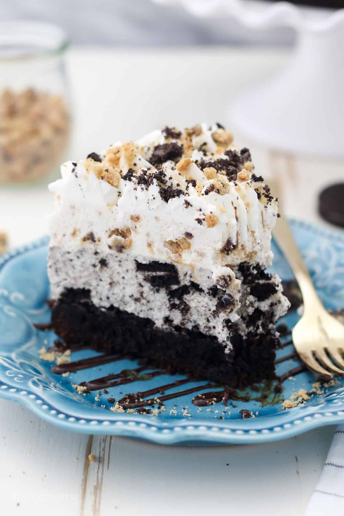 A slice of Oreo brookie mousse cake on a blue plate with a fork.