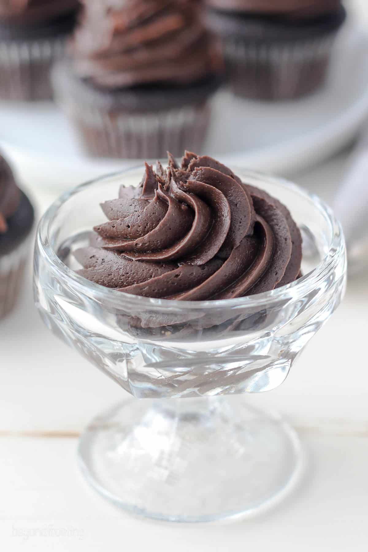 A swirl of chocolate cream cheese frosting in a glass bowl.