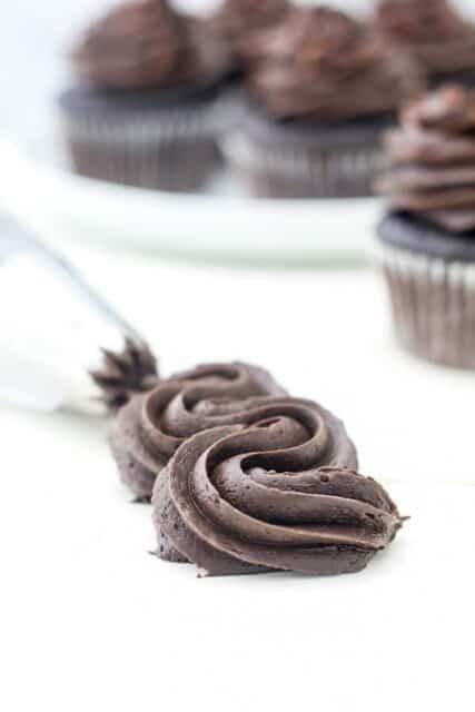 A swirl of chocolate frosting piped onto a white surface.