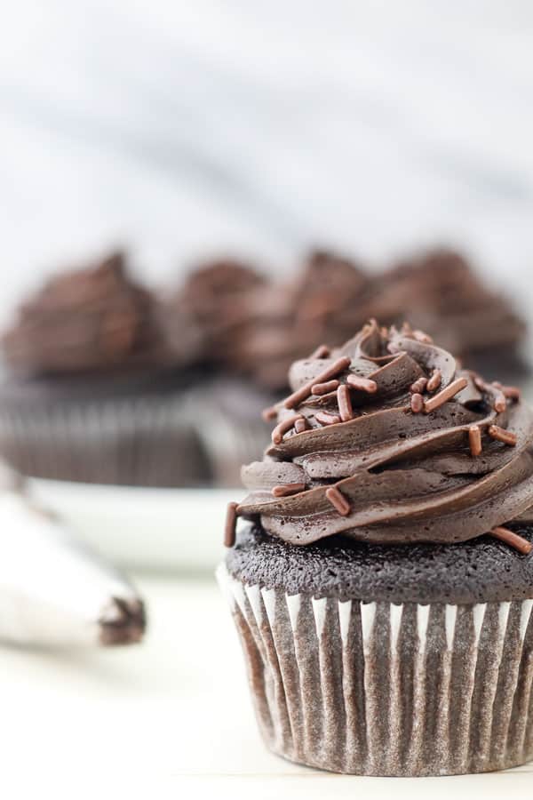 A chocolate cupcake frosted with chocolate frosting with chocolate sprinkles.