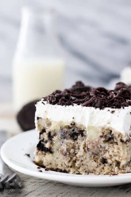 Een close up foto van een plakje cookies and cream cake gegarneerd met slagroom en Oreo's