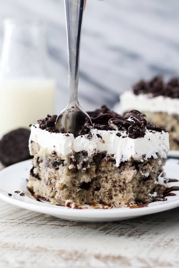 A silver fork sinking into a slice of Oreo cake