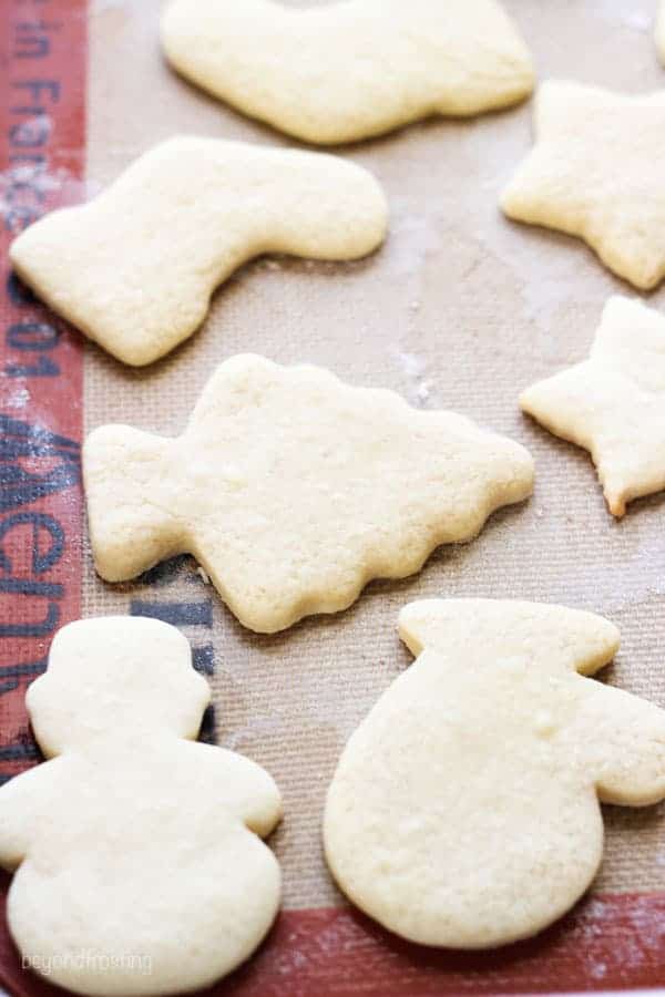 A baking tray lined with a silicone baking mat, with baked sugar cookies on it.