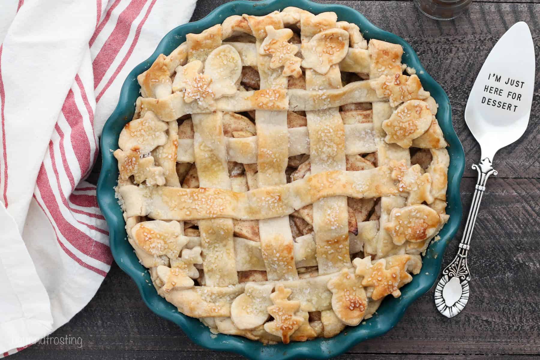 An overhead shot of a lattice topped apple pie in a dark teal pie plate