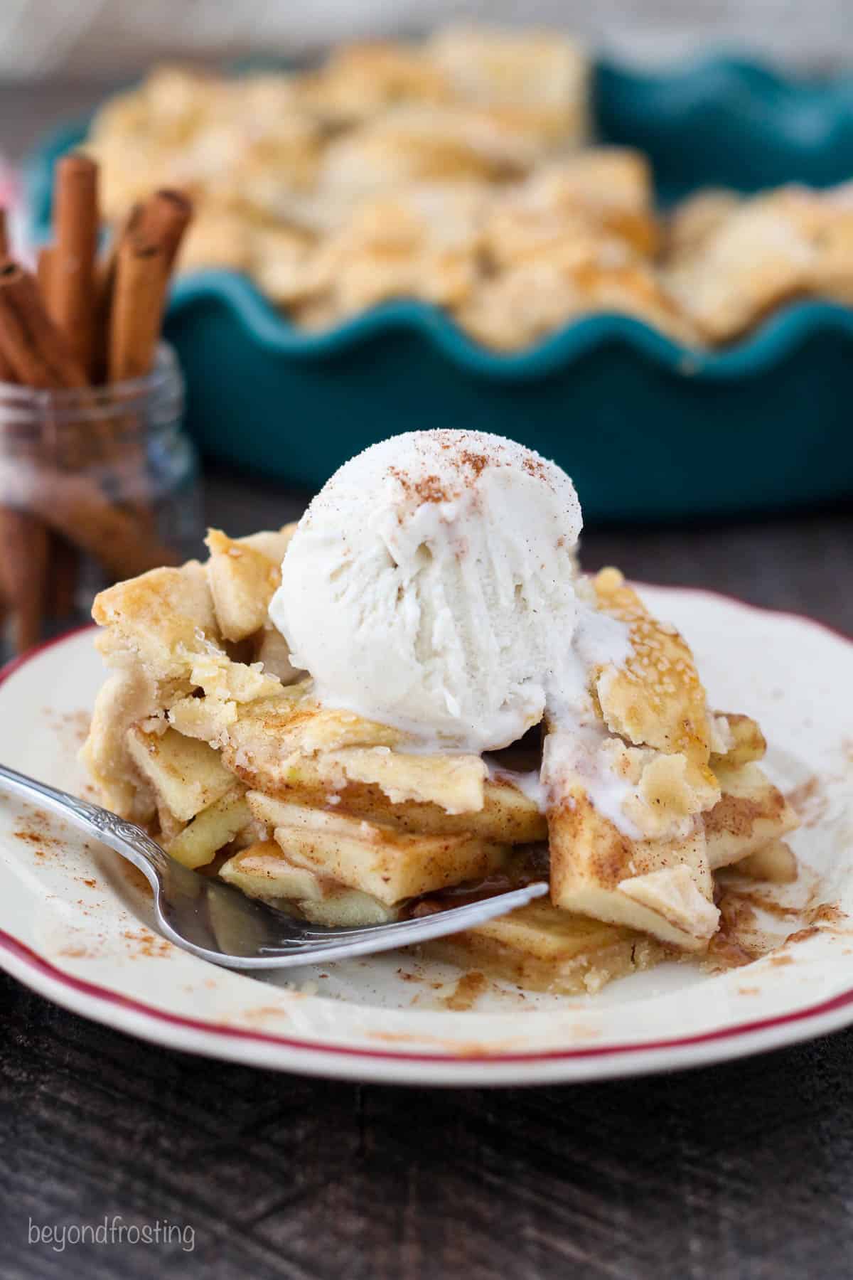 A plate of apple pie with a big bite missing and a heaping scoop of ice cream on top