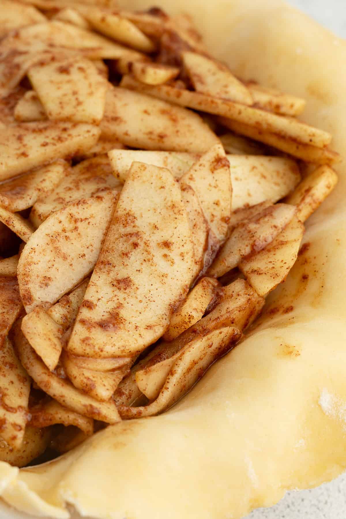 Close up of apple pie filling inside a pie crust.