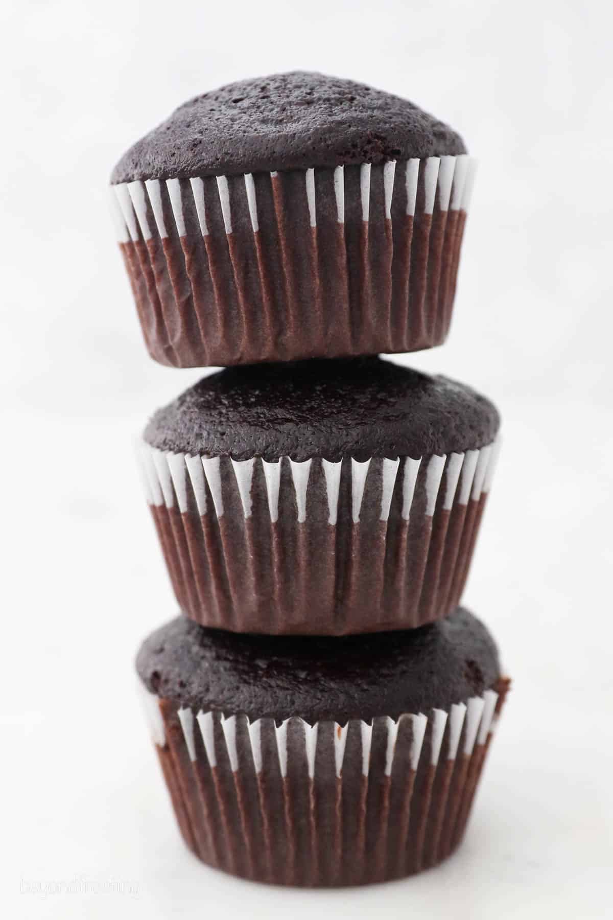 Three chocolate cupcakes stacked on top of one another.