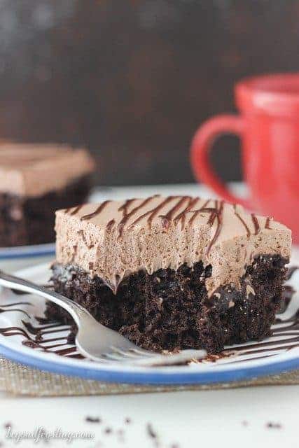 A slice of Hot Chocolate Poke Cake with a bite missing and a fork resting next to it.