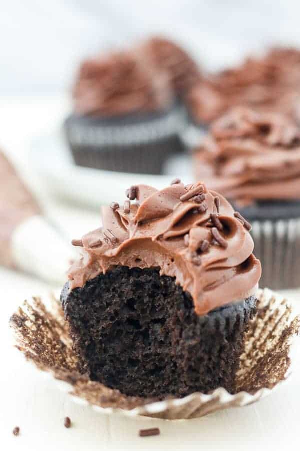 A big bite is taken out of a chocolate cupcake showing all the air bubbles inside