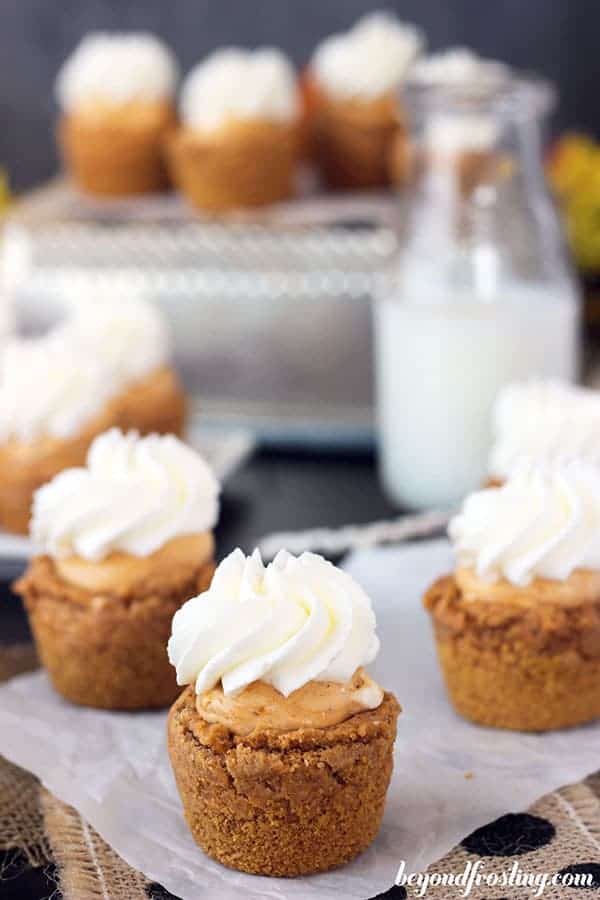 An overhead shot of a group of mini cookie cups, with a pumpkin filling and whipped cream