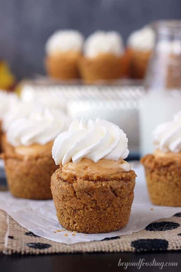 A little pumpkin cookie with a mousse filling and whipped cream on top, there are 3 of them lined up.