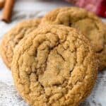 A close up shot of a molasses cookie leaving up against a stack of more cookies