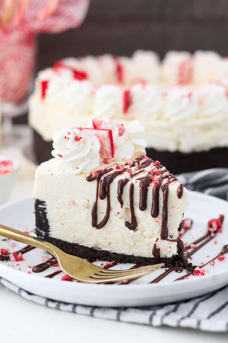 a tall slice of a peppermint cheesecake on a white round plate with a gold fork