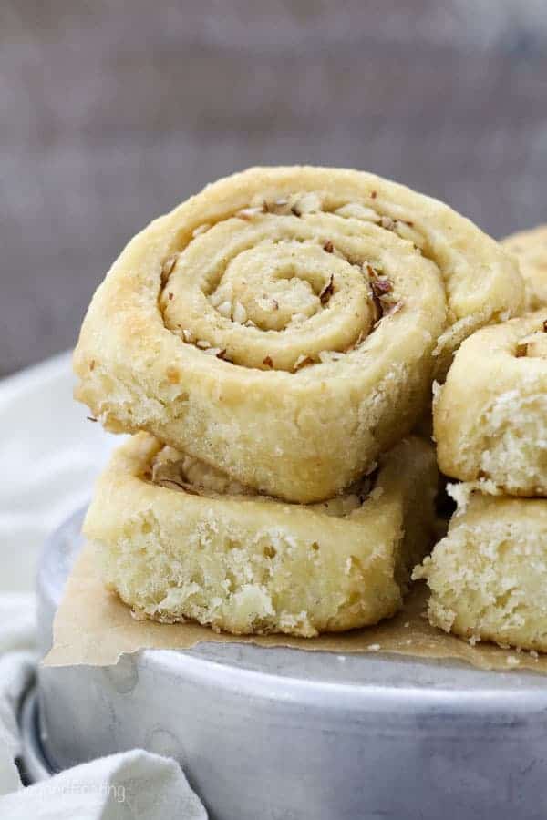 Stacked morning buns on a silver cake plate. The morning bun is sprinkled with crushed almonds