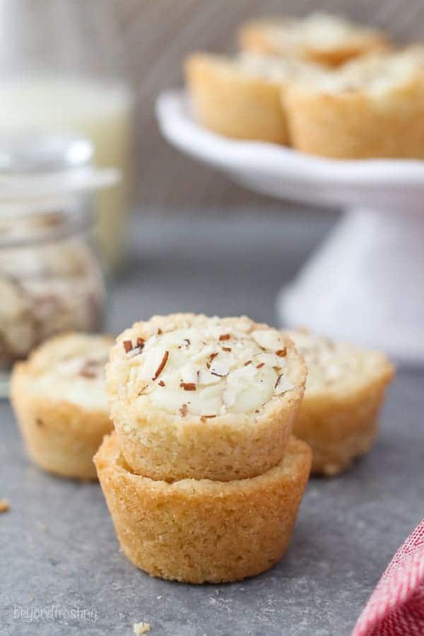 Two mini cookie cups stacked, the cookie on top has diced almonds on top.