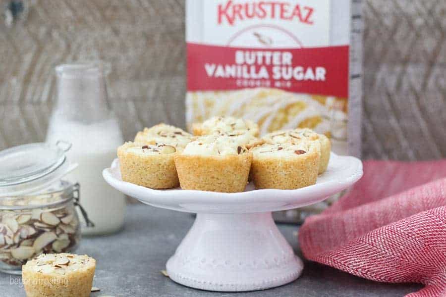 A small white cake stand with mini cookie cups on top and a box of Krusteaz Butter Vanilla Sugar Cookies in the background