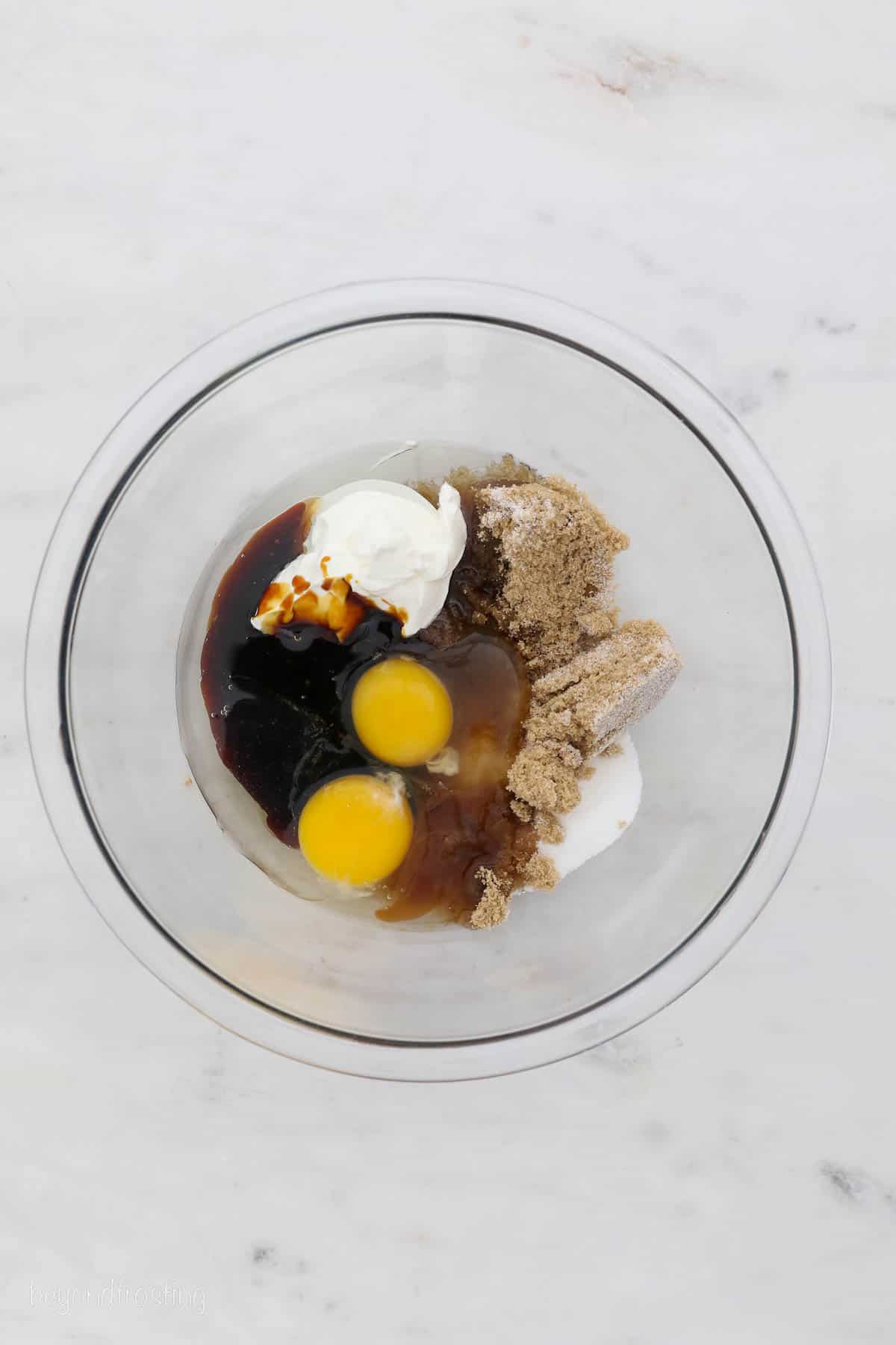 Overhead view of wet gingerbread cupcake batter ingredients in a glass bowl.