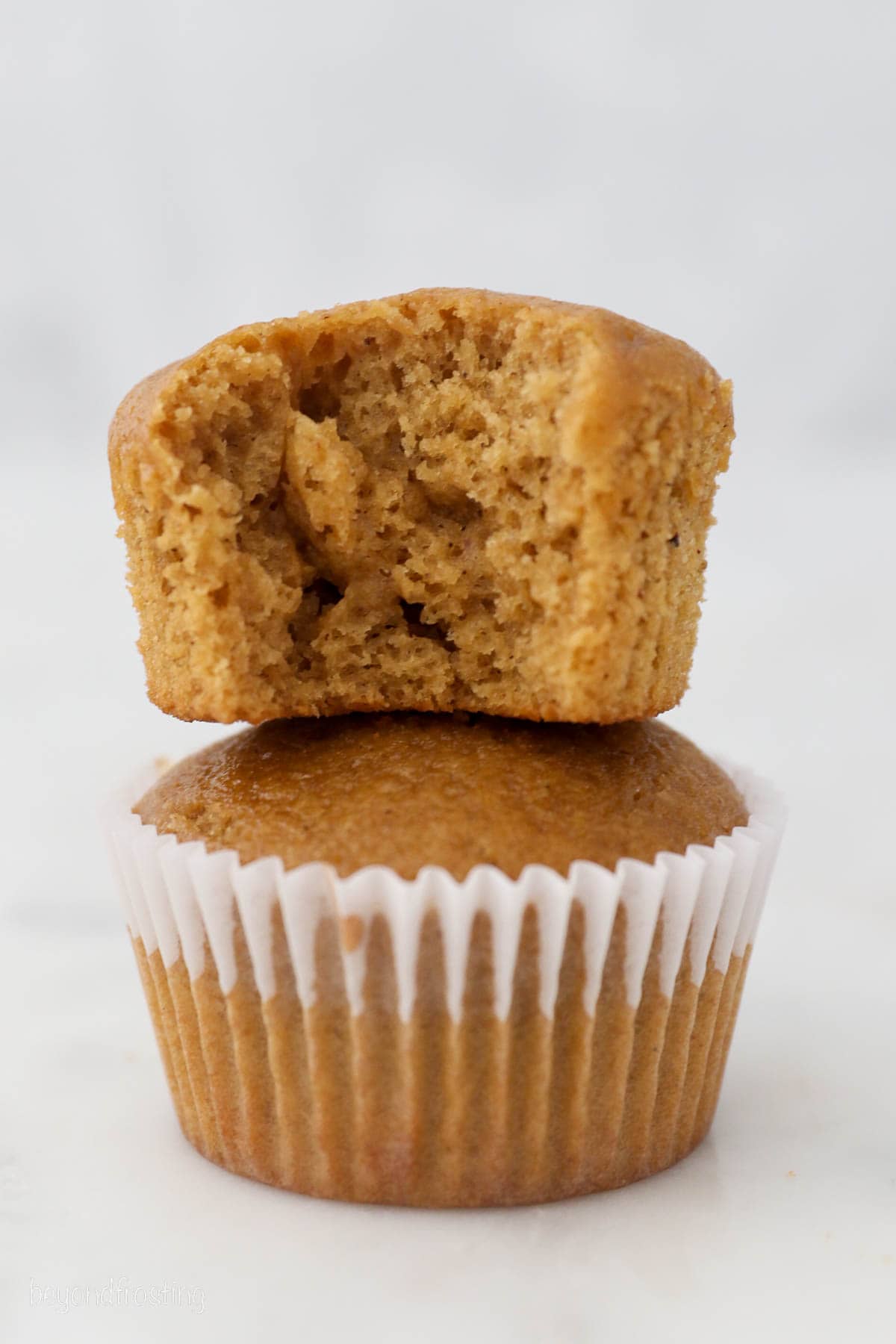 Two unfrosted gingerbread cupcakes stacked on top of one another.