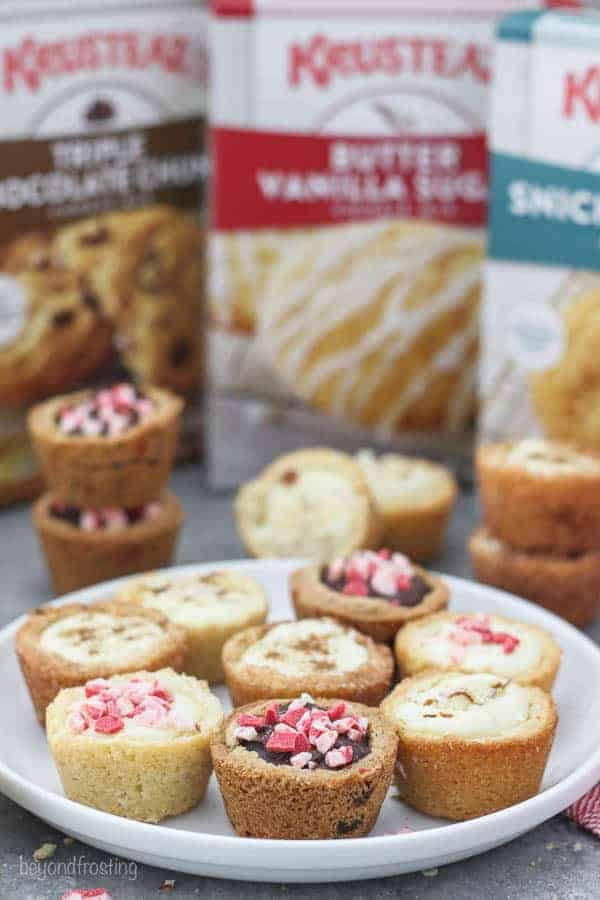 A white rimmed plate filled with various cookie cups and 3 boxes of Krusteaz cookie mix in the background.